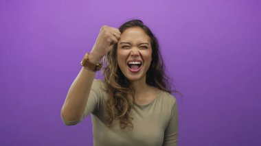 Gülümseyen enerjik İspanyol kadın, izole edilmiş parlak mor bir stüdyoda parmakları olan üç kişi sayıyor; heyecan..
