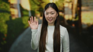 Şehir merkezindeki bir sokakta el sallayan bir kadın güpegündüz neşeli ve dostane bir tavır sergiliyor..