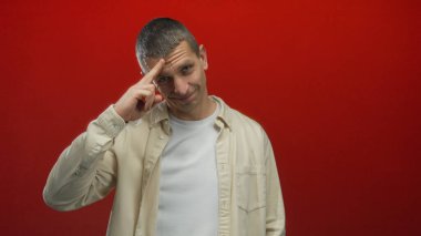 Bej gömlekli, neşeli bir gülüşü olan, canlı kırmızı bir arkaplanı olan ve bir anlık pozitiflik ve dostluk yakalayan bir adam..