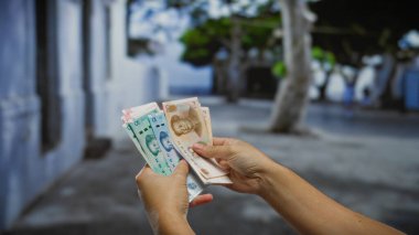 Çin Yuan 'ı elinde tutan bir adam, şehir merkezinde bir sokakta döviz ve iş alışverişi sergiliyor..