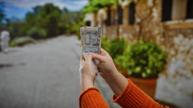 Peru tabanını şehir ortamında tutan eller açık havada paralara odaklanan bir kadınla bulanık şehir arka planına karşı..