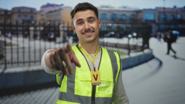 Yansıtıcı yelek giyen genç İspanyol adam şehir sokaklarında gönüllü olarak çalışıyor. Şehir dışında kamu hizmeti faaliyetlerine katılıyor.