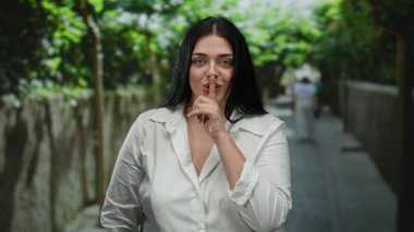 Bir kadın şehir caddesinde dışarıda dikilirken sessiz hareketler yapıyor, sakin ve huzurlu bir atmosferi somutlaştırıyor gün ışığında kentsel çevrede..