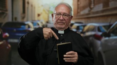 Elinde kitap mimikleri olan yaşlı bir rahip kalabalık bir caddede arabalarla dikilirken, açık bir şehir ortamında halka açık bir vaaz veriyor..