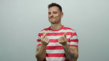 Genç adam, izleyiciyle iletişim kurarken özgüvenini ve çekiciliğini ifade ederek izole beyaz arka planda para hareketi yapıyor..