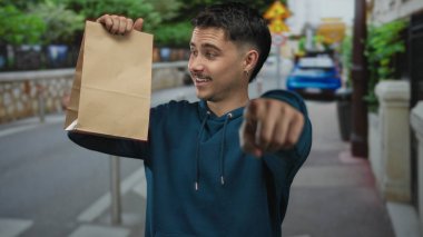 Şehrin sokaklarında elinde kağıt torbalarla gezen genç bir İspanyol, neşeli bir şekilde dışarıya bakıyor. Heyecanlı ve canlı bir ifade sergiliyor..