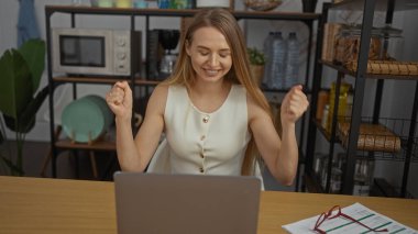 Görevdeki başarısını dizüstü bilgisayarla kutlayan kadın, masa başında kağıtlar ve arka planda raflar kapalı alanda verimli bir çalışma ortamı öneriyor.