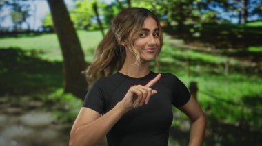 Sarışın kadın, güneş ışığı altındaki ormanda el ele tutuşarak saçların hafifçe eserken, kendine güvenen bir oyuncu olduğunu gösteriyor..