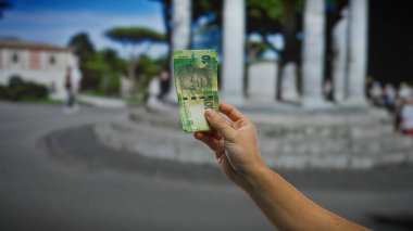 Kentsel ortamda Güney Afrika Rand 'inin elini tutmak, şehir zeminine karşı para birimini vurgulamak, hareketli şehir ortamındaki mali işlemleri sembolize etmek.