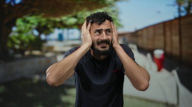 Sakallı İspanyol bir adam, güneşli bir çevrede sokakta hayal kırıklığına uğramış görünüyor..