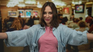 Canlı resimler ve izleyicilerle sanat galerisi ortamında gülümseyen bir kadın, rahat bir sanat ortamında mutluluk ve kültürel bağlantıyı somutlaştırıyor..