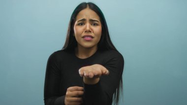 Bir kadın, arka planda genç bir Latin 'in mavi bir duvara karşı elini tutup yalvararak poz veriyor..