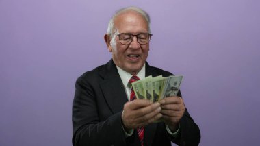 Üst düzey bir adam bize dolar banknotları sayarak mor bir arka plan, sergilenen iş başarısı ve finansal bolluk karşısında.