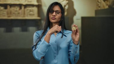 Müzede elinde bozuk para tutan kadın, dijital para kavramını içeriden vurgulayarak ihtiyatlı davranışta bulunuyor..