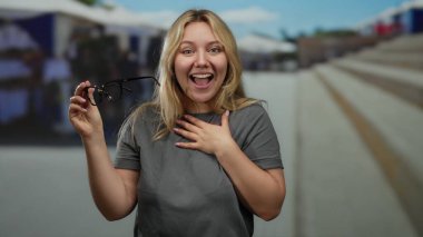 Güneşli bir günde arka planı bulanık bir şekilde elinde bardak tutan bir kadın..