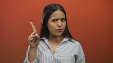 Kadın parmağı arka planı işaret ediyor. Latin kökenli genç, izole edilmiş kırmızı duvar taşıyıcıları reddediyor..