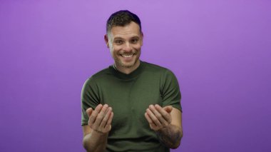 Genç adam mor bir duvara karşı jestler yapıyor, duygularını dışa vuruyor ve özgüvenli bir gülümseme ve günlük bir stil ile etkileşime giriyor..