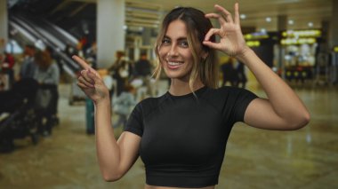 Çıplak kollu, gülümseyen ve sağa sola işaret eden bir kadın dükkânda 