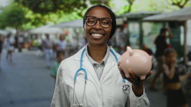 Kadın doktor, elinde kumbarayla elinde domuz kumbarasıyla, arka planda güneşli gökyüzü ve ağaçların altında refahı ve tasarrufu temsil eden insanlarla finans sağlığını sergiliyor.