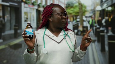 Sokakta gülümseyen bir kadın elinde steteskopla ilaç şişesiyle, açık havada sağlık bilincini ve şehir yaşam tarzını ön plana çıkarıyor..