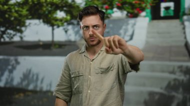 Sakallı genç adam, şehir sokaklarında yeşil çizgili parmakla 