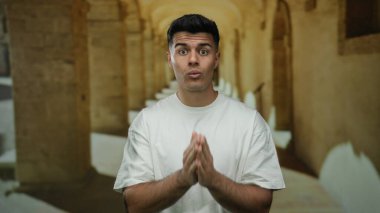 Beyaz gömlekli genç adam tarihi üniversite koridorunda duruyor ve duygularını aktarıyor..