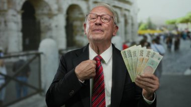 Takım elbiseli son sınıf öğrencisi elinde Czech Koruna banknotları Roma Kolezyum Caddesi 'nin yakınındaki açık havada el kol hareketleri yapıyor..