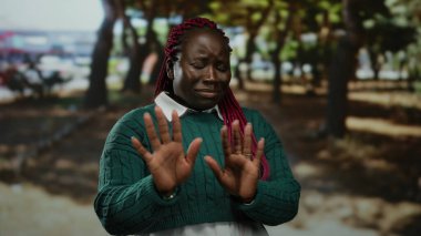 Parkta reddedilen bir kadın, çevresindeki ağaçlarla canlı çevre ve gün ışığı altında doğal elementlerle birlikte açık hava sahnesini gösteriyor..