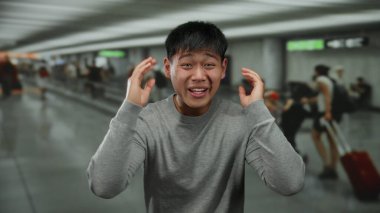 Havaalanı terminalinde hayal kırıklığını ifade eden genç bir adam. Etrafı bulanık yolcularla çevrili. Seyahat stresi ve yoğun bir ev ortamını aktarıyor..