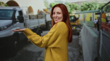 İnşaat alanında sarı bir kazakla gülümseyen bir kadın, kendinden emin ve neşeli bir ifade sergiliyor endüstri teması için ideal..