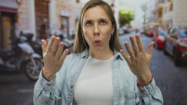 Genç sarışın kadın şehir caddesinde boynuna ve göğsüne dokunuyor; sıcaklık yorgunluğu.