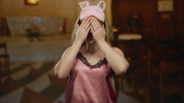 Gece kıyafetli genç bir kadın Katolik kilisesinde elleri ile neşeli bir şekilde yüzünü örtüyor. Huzurlu ve ruhani bir ortamda masumiyet ve merakın bir karışımını yakalıyor..