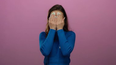 Oy kartı olan genç bir kadın, Amerika Birleşik Devletleri seçimlerinde oy verdikten sonra neşeli ifadeler ve neşeli ruh hali gösteren pembe arka planda komik suratlar yapıyor.