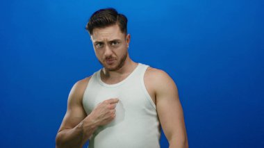 Sakallı genç adam kendini gösteriyor ve kendine güvenen bir ifadeyle mavi duvara işaret ediyor..