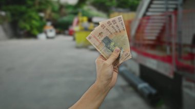 Bir şehir caddesinde elinde Romen leu banknotları tutan adam, gündelik bir ortamda Romanya para birimi üzerinde yoğunlaşarak kentsel açık hava finansmanının özünü yakalıyor..