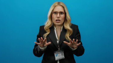 Mavi bir arkaplanda, iş elbisesi ve gözlük takan, kimlik gösteren, profesyonel bir ortamda aciliyet ve gerilimi aktaran bir kadın..