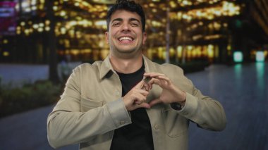 İnsan şehir merkezinde elleri ile kalp şeklini oluşturur; aşk, mutluluğu etkiler..