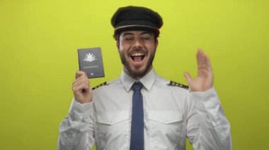 Mutlu pilot üniforması giyiyor, gülümsüyor ve elinde parlak sarı arka planda Avustralya pasaportu var.