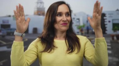 Genç İspanyol kadın tarihi bir meydanda duruyor ve elleriyle büyük bir jest yapıyor; ölçü karşılaştırması..