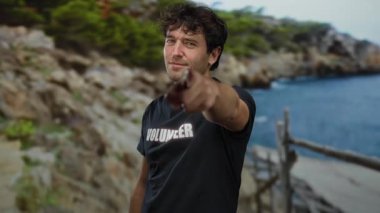 Deniz kenarındaki Rocky Plajı 'nda kamerayı işaret eden yakışıklı gönüllü kendini adamış ve sahilin ortasındaki toplum ruhunu sergiliyor..
