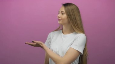 Farklı seçenekler sunan bir kadın, pembe arka planda, izole edilmiş beyaz bir gömlek giyiyor, kendine güvenen genç bir ifade sergiliyor ve seçenekler sunuyor..