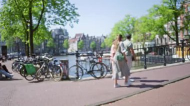 Güneşli bir günde, bisiklet ve tarihi binalarla dolu bir kanalda gezen insanların bulanık manzarası canlı bir şehir zemini yaratıyor..