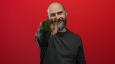 Sakallı adam barışı işaret eder ve enerjik bir şekilde izole edilmiş kırmızı bir arkaplanı işaret eder, anlamlı ve canlı bir portre yaratır..