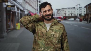 Üniformalı İspanyol askeri kalabalık bir sokakta boynunu sıvazlarken acı içinde dikiliyor..