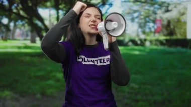 Bir gönüllü etkinlik sırasında elinde megafonla parkın dışında tutkuyla konuşan bir kadın..