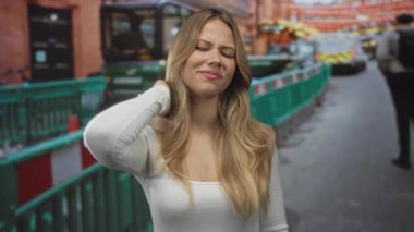 Beyaz gömlekli bir kadın inşaat alanında boynunu tutarken irkildi. Ağrı yorgunluğu, yorgunluk ve yorgunluk..