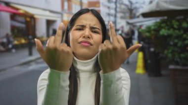 Yoğun şehir caddesinde beyaz elbiseler içinde küstah bir ifade sergileyen bir kadın güçlü duygular ve şehir gençlik kültürü öneriyor..