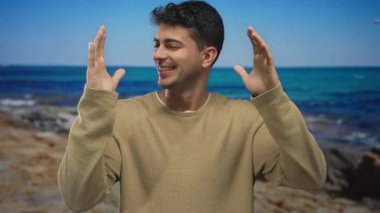 Genç İspanyol kaşif erkek yüzünde parlak bir tebessümle deniz ve okyanus ufkuna hayranlık duyarken adam sahilde el kol hareketi yapıyor..