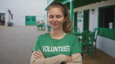 Kadın kolları çapraz avluda gülümseyen sarışın genç gönüllü tişört yeşil duruş güven veriyor..