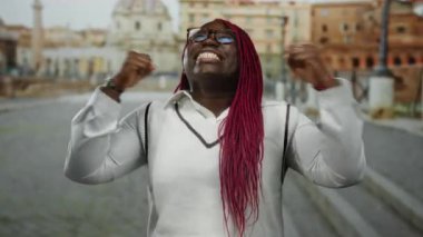 Roma harabelerinin arkaplanına karşı kollarını kaldırarak kutlama yapan kadın şehir sokaklarında neşe ve heyecan ifade ediyor..